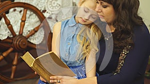 Mother and child girl reading a book in bed before going to sleep