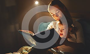 Mother and child girl reading a book in bed photo