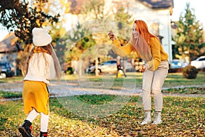 Mother and child girl throwing leaves in autumn park. Autumn holidays, lifestyle, childhood