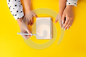 Mother and child hands writing in a notepad, top view