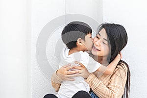 Mother and child happily hugged and kissed each other`s cheeks. Asian family mom and child are hugging and fragrant, cheeks