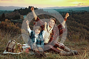 Mother and child hikers rejoicing while sitting on blanket