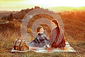 Mother and child hikers in Tuscany on sunset sitting on blanket