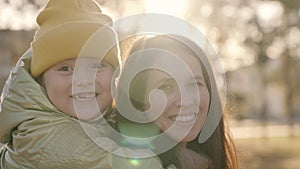 mother and child hug at sunset of autumn in city, happy family, mother and kid laugh in their arms in light of sun