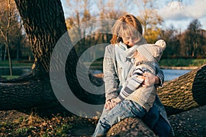 Mother and child hugging at autumn park near the lake