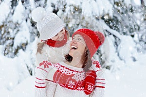 Mother and child in knitted winter hats play in snow on family Christmas vacation. Handmade wool hat and scarf for mom and kid.