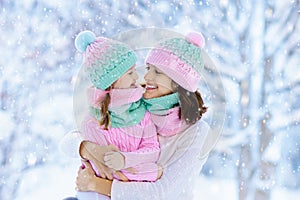 Mother and child in knitted winter hats play in snow on family Christmas vacation. Handmade wool hat and scarf for mom and kid.