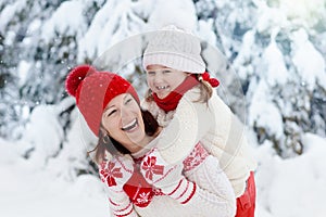 Mother and child in knitted winter hats play in snow on family Christmas vacation. Handmade wool hat and scarf for mom and kid.