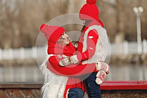 Mother and child in knitted winter hats play in winter park