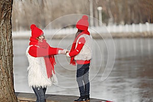 Mother and child in knitted winter hats play in winter park