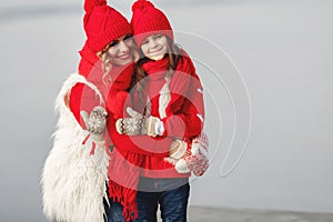 Mother and child in knitted winter hats play in winter park