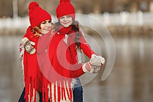 Mother and child in knitted winter hats play in winter park