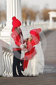 Mother and child in knitted winter hats play in winter park