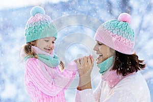 Mother and child in knitted winter hats in snow.