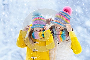 Mother and child in knitted winter hats in snow