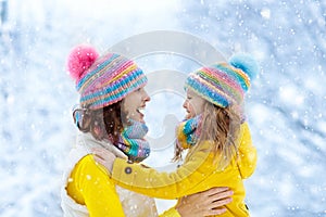 Mother and child in knitted winter hats in snow