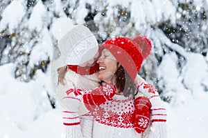 Mother and child in knitted winter hats in snow