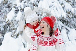 Mother and child in knitted winter hats in snow