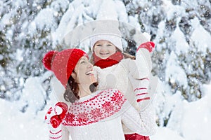 Mother and child in knitted winter hats in snow