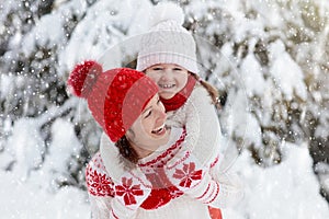 Mother and child in knitted winter hats in snow