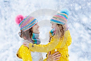 Mother and child in knitted winter hats in snow