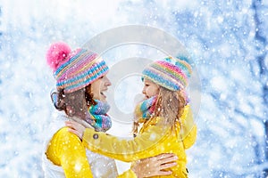 Mother and child in knitted winter hats in snow