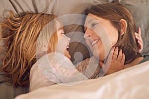 Mother, child and laughing on bed with love for relax, bonding together and fun weekend in family home. Mom, happy and