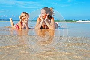 Mother with child lying in water pool at sea beach