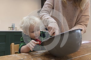 Mother and child mixing ingredients in a bowl in the kitchen together.