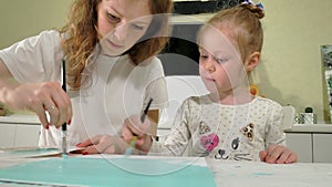 Mother and child paint with colored brush. Games with children affect the development of early children.