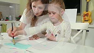 Mother and child paint with colored brush. Games with children affect the development of early children.