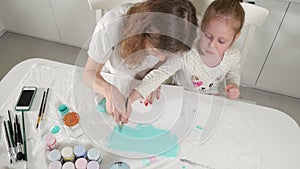 Mother and child paint with colored brush. Games with children affect the development of early children.