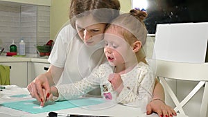 Mother and child paint with colored brush. Games with children affect the development of early children.