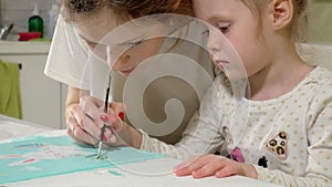 Mother and child paint with colored brush. Games with children affect the development of early children.