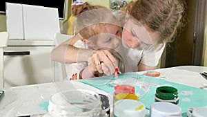 Mother and child paint with colored fingers. Games with children affect the development of early children.