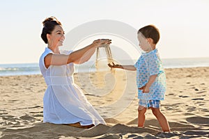Mother with child play with sand on sea beach