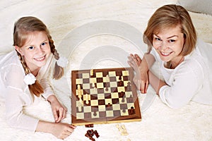 Mother and child are playing chess while spending time together at home.