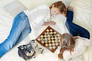 Mother and child are playing chess while spending time together at home.