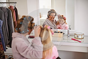 Mother, child and playing with hair in mirror for beauty, care and helping or getting ready. Excited mom, family and