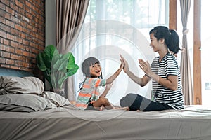Mother and child playing highfive on the bed