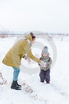 Mother and child playing with snow outside on a winter day