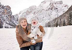 Mother and child playing with snow among snow-capped mountains