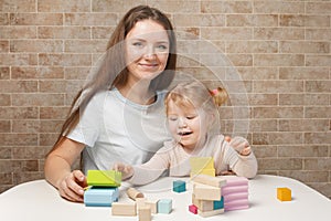 Mother with a child playing with wooden blocks at home