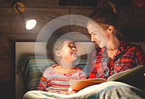 Mother and child reading book in bed before going to sleep