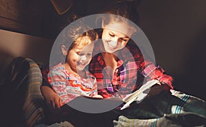 Mother and child reading book in bed before going to sleep