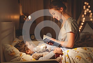 Mother and child reading book in bed before going to sleep