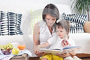 Mother and child, reading a book and eating fruits