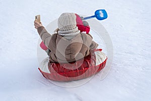 mother with a child rides down a hill on ice floes and takes pictures of herself on a phone camera