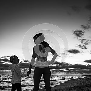 Mother and child on seacoast on sunset looking at each other