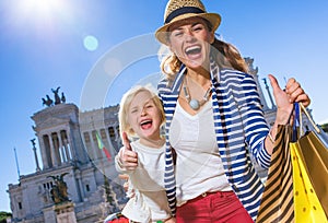 Mother and child with shopping bags showing thumbs up